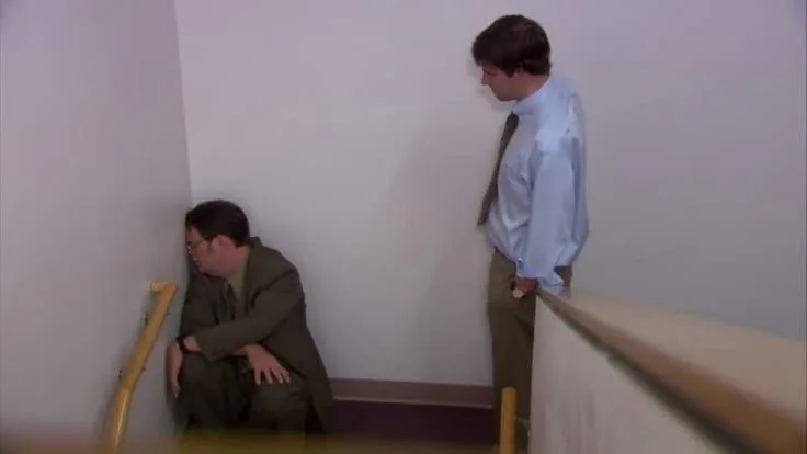 A man sitting on a stairway while another person looks on