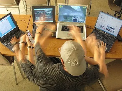 A person working across several laptops